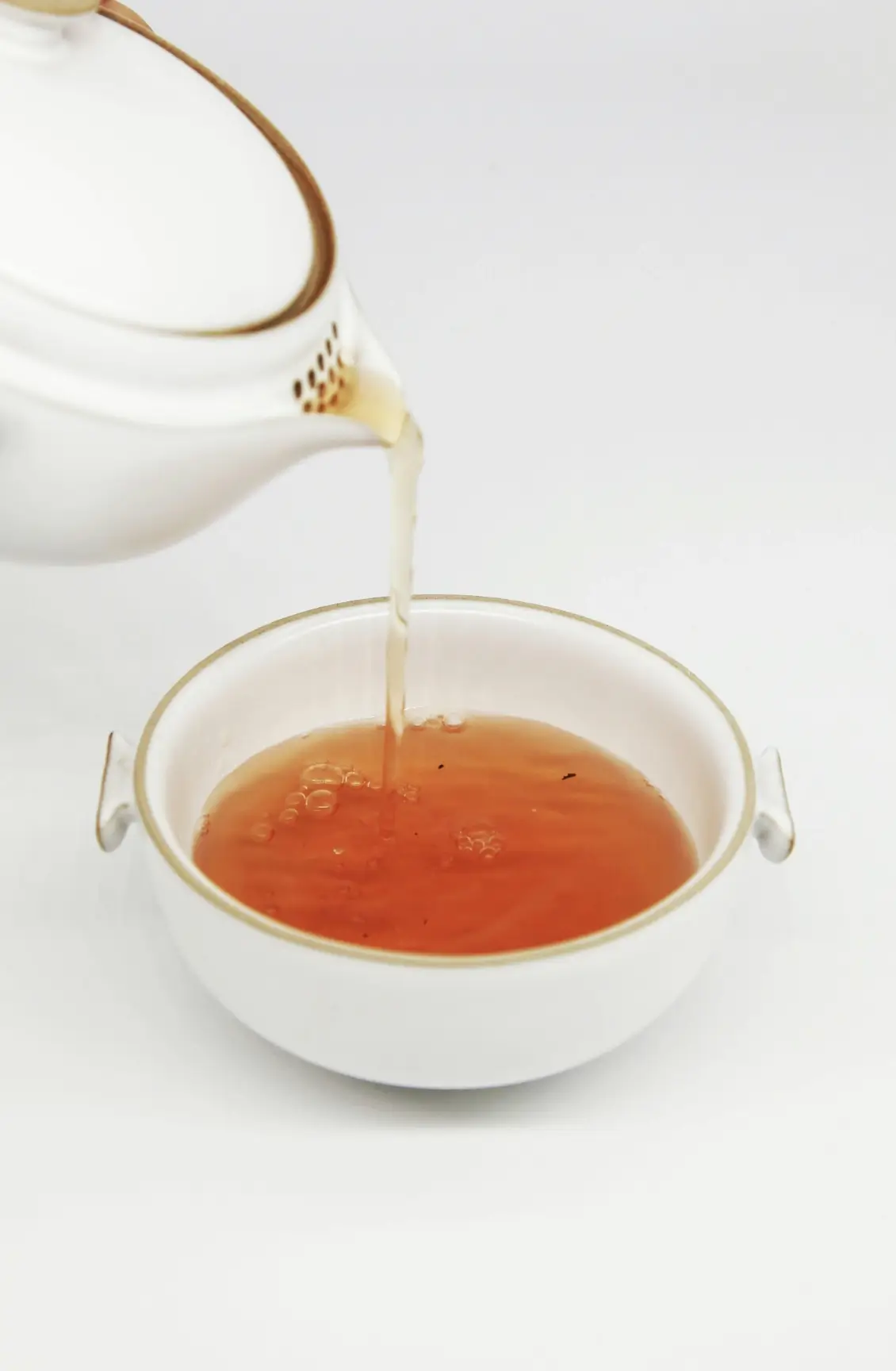 Tisane orangée versée dans une tasse blanche